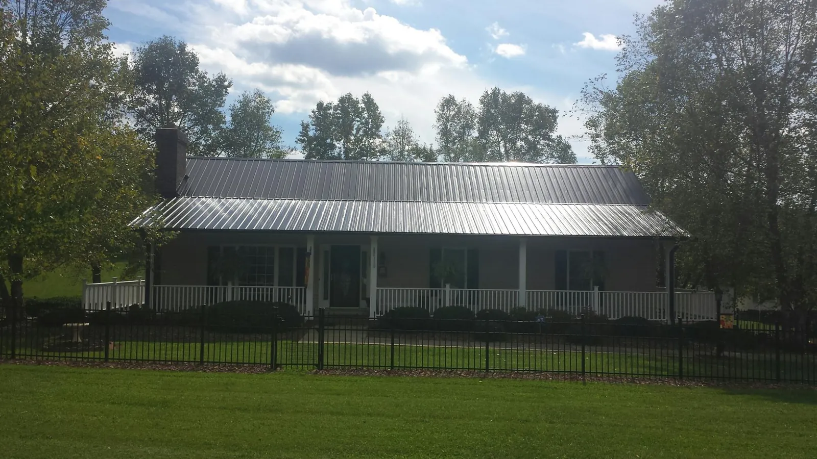 Gray metal roof on a brick ranch with a full width front porch — Gutter Guard Installation work by our crew in Adams