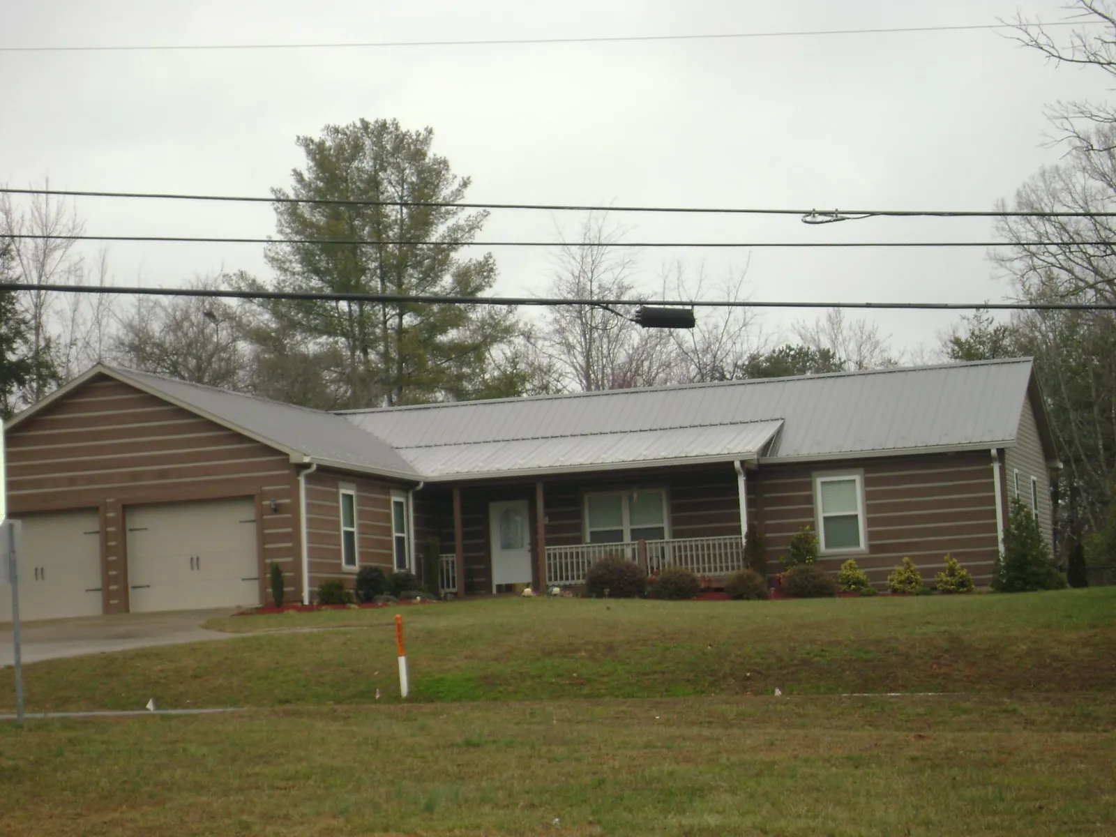 Gray metal roof on a log sided ranch home with a front porch in Adams